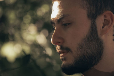 Close-up portrait of young man looking away outdoors