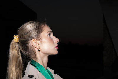 Close-up of young woman looking away against black background