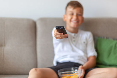 Midsection of man using mobile phone while sitting on sofa at home