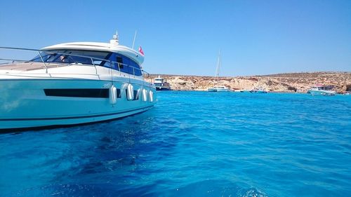 Boat in sea against clear blue sky