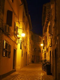 Empty alley amidst buildings at night