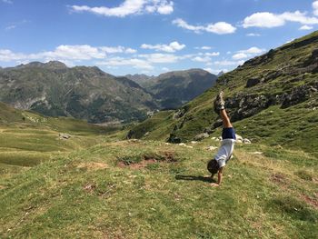 Full length of boy doing handstand against mountain and sky