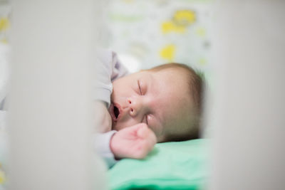 Close-up of cute baby boy sleeping on crib
