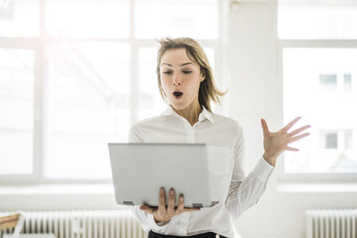 Amazed woman holding laptop