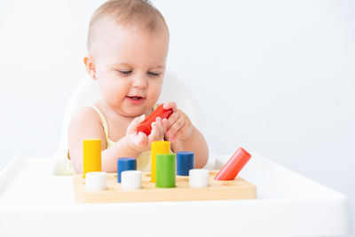 Close-up of boy playing with toy blocks against white background