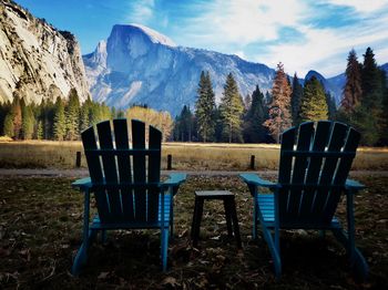 Chairs and tables on field against sky