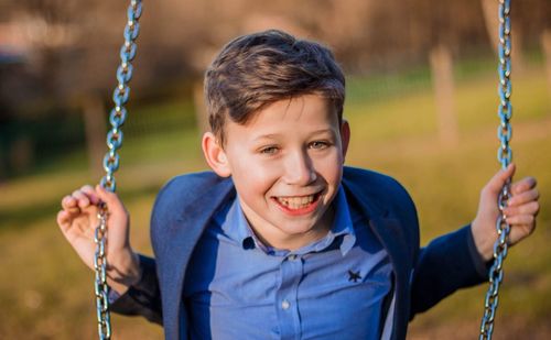 Portrait of smiling boy on swing at playground