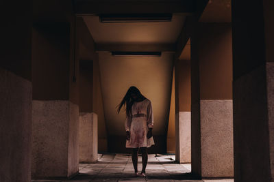 Rear view of woman walking in corridor of building