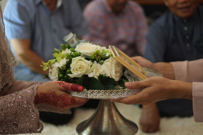 Cropped hands of wedding couple holding bouquet