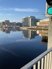 Bridge over river by buildings in city against sky