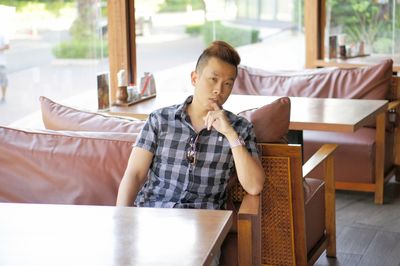 Portrait of young man sitting at table in restaurant