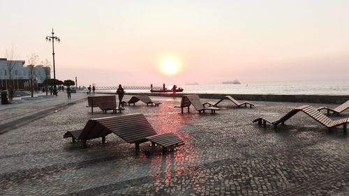 People on beach against sky during sunset