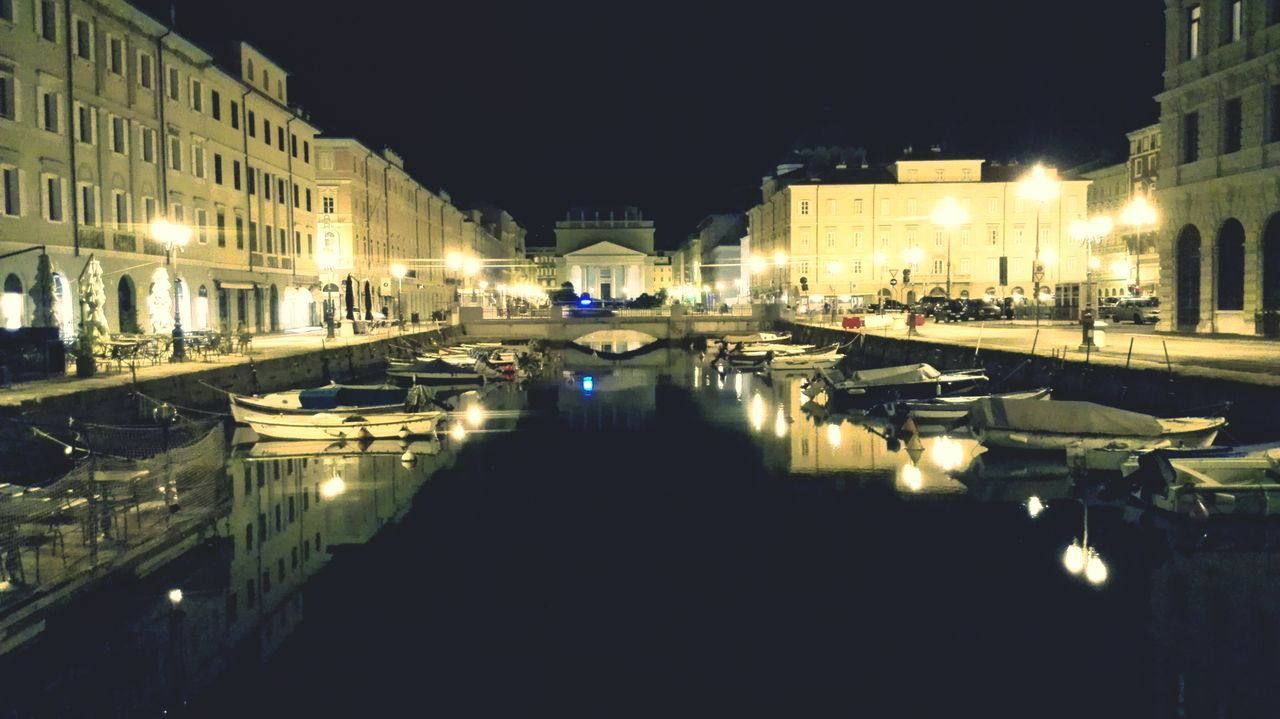 night, illuminated, building exterior, architecture, built structure, water, reflection, street light, city, waterfront, canal, lighting equipment, clear sky, transportation, river, city life, outdoors, incidental people, building, residential building