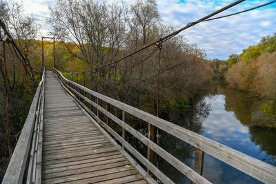 Footbridge amidst trees against sky