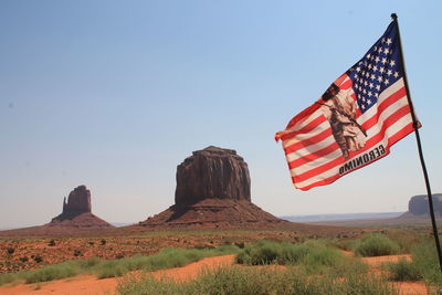 Red flag on rock formation against clear sky