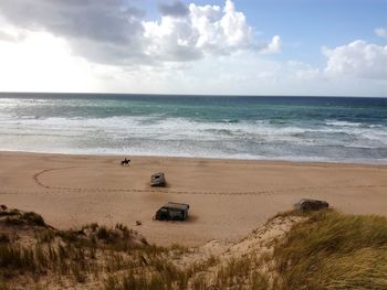 Scenic view of beach against cloudy sky