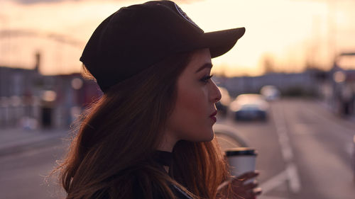 Side view of young woman against sunset sky