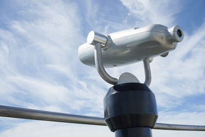 Low angle view of coin-operated binoculars against cloudy sky