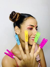 Close-up of young woman with clothespins on fingers against wall