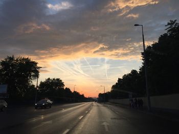 Cars on road against sky during sunset