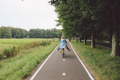 Rear view of woman riding bicycle on road