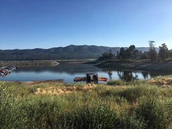 Scenic view of river and mountains against clear blue sky