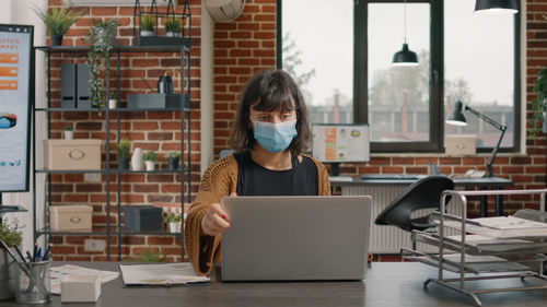 Rear view of woman using laptop at cafe