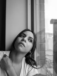 Beautiful woman looking through window at home