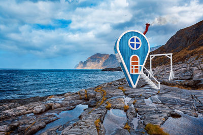 Information sign on rock by sea against sky