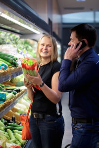 Happy young couple shopping at greengrocer shop