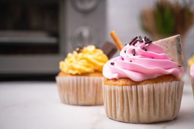 Delicious homemade cupcakes with colorful cream and topping with candy and chocolate cookies.