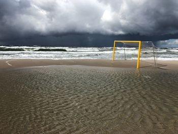 Goal post at beach against storm clouds
