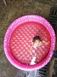 Directly above view of cute girl in pink wading pool at back yard