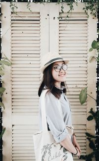 Portrait of happy woman standing against closed door