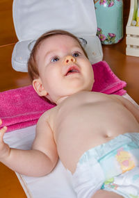 Cute baby girl lying on bed at home