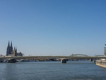 Bridge over river against sky in city