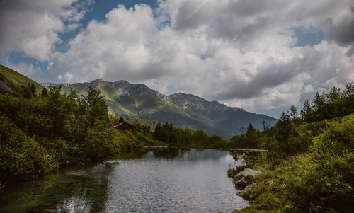 Scenic view of river by mountains against sky