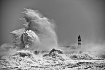 Lighthouse amidst sea against sky