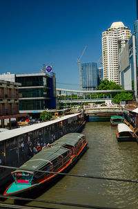Bridge over river by buildings against sky in city