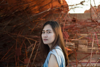 Portrait of young woman standing against tree