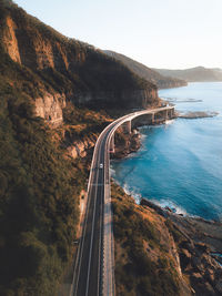 Scenic view of road by sea against clear sky