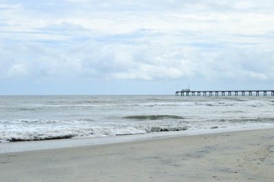 Scenic view of beach against cloudy sky