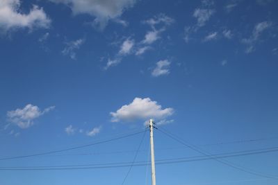 Low angle view of electricity pylon against blue sky