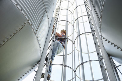 Farmer climbing up ladder at tank