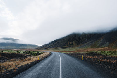 Road leading towards mountains against sky