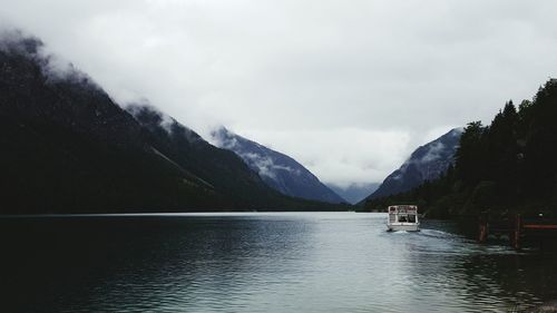 Scenic view of lake and mountains against cloudy sky