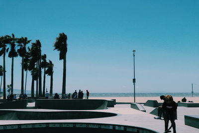 People at skateboard park against blue sky