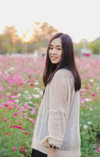 Portrait of young woman standing against plants