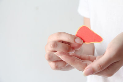 Cropped hand of person holding dentures against white background