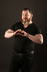 Portrait of mature man standing against black background